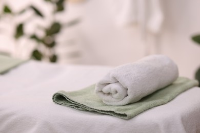 Rolled towel on massage table in spa center. Space for text