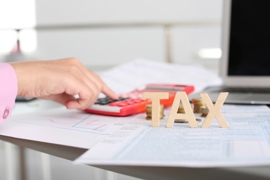 Photo of Young female calculating taxes at table, closeup