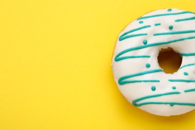 Tasty glazed donut on yellow background, top view. Space for text