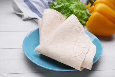 Photo of Delicious folded Armenian lavash and fresh vegetables on white wooden table, closeup