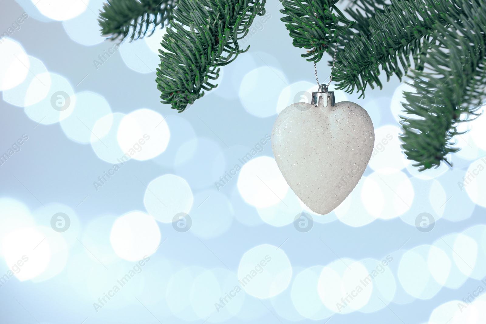 Photo of Beautiful holiday bauble hanging on Christmas tree against blurred lights, closeup. Space for text
