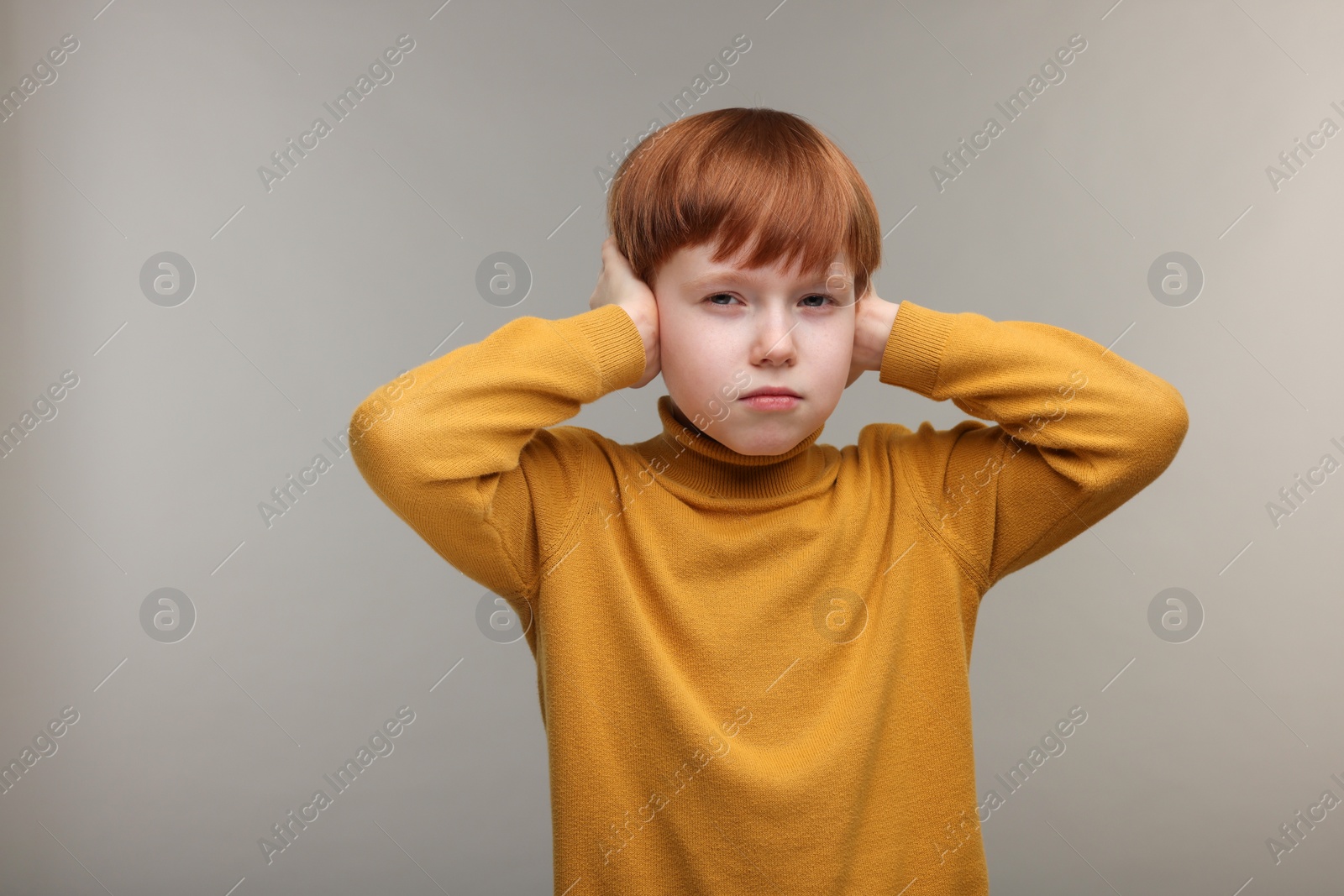 Photo of Hearing problem. Little boy suffering from ear pain on grey background, space for text