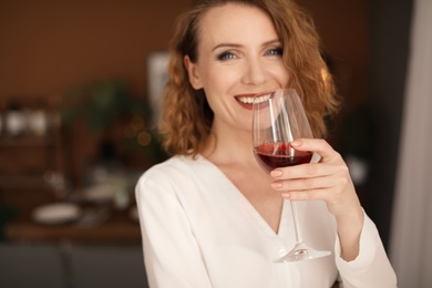 Woman with glass of delicious wine indoors