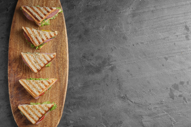 Photo of Tasty sandwiches with ham on grey table, top view. Space for text