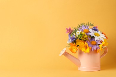 Pink watering can with beautiful flowers on yellow background, space for text