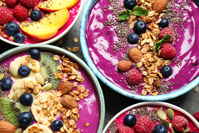 Image of Delicious acai smoothie with toppings in bowls on table, flat lay