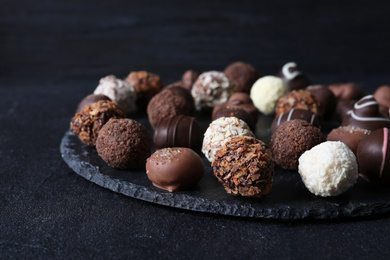 Photo of Different tasty chocolate candies on black table