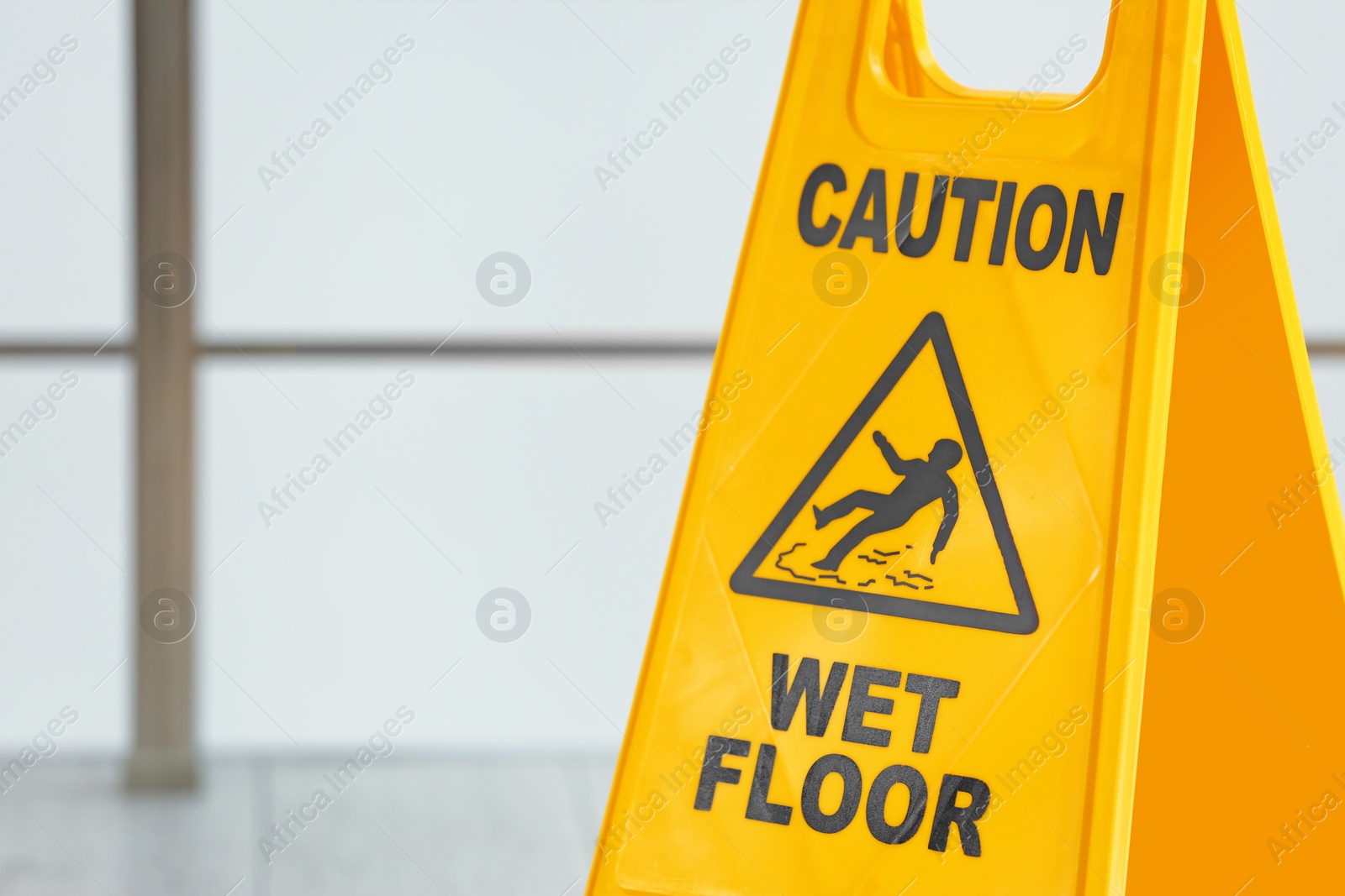 Photo of Safety sign with phrase Caution wet floor on blurred background. Cleaning service