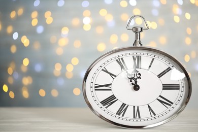 Photo of Clock showing five minutes until midnight on blurred background, space for text. New Year countdown