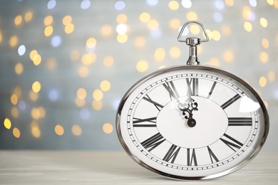 Clock showing five minutes until midnight on blurred background, space for text. New Year countdown