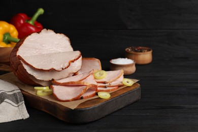 Photo of Delicious cut ham served on black wooden table. Space for text