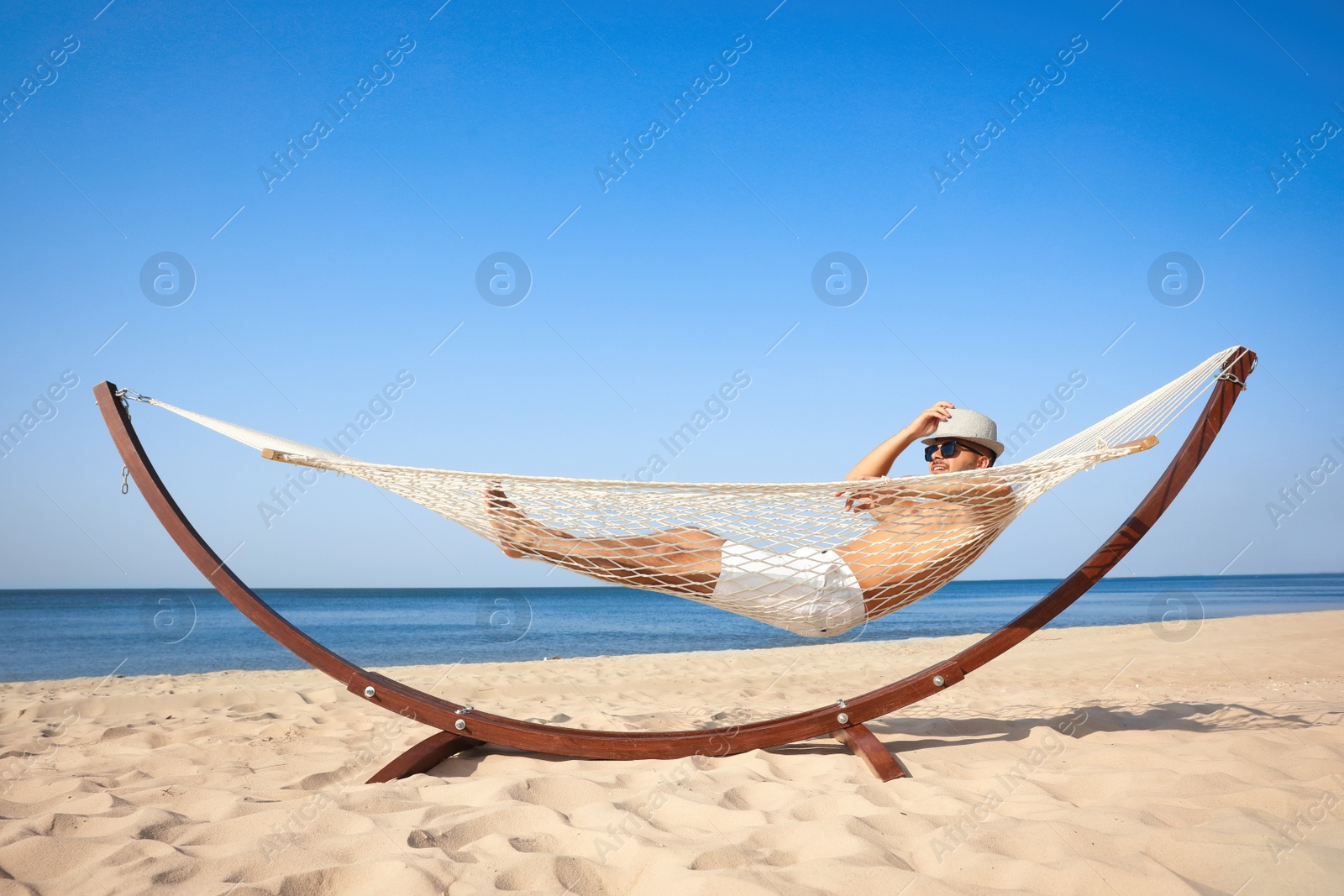 Photo of Young man relaxing in hammock on beach