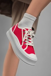 Photo of Woman posing in red classic old school sneakers on light gray background, closeup