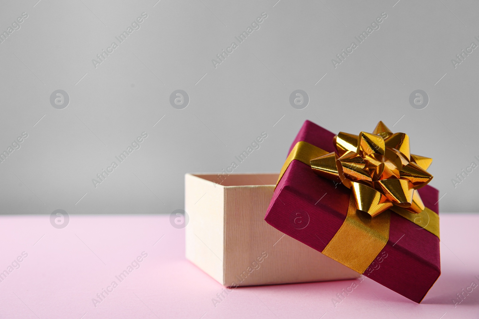 Photo of Beautiful open gift box on pink table. Space for text