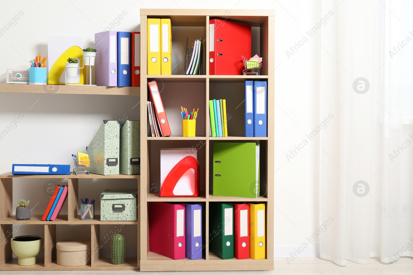 Photo of Colorful binder office folders and other stationery on shelving unit indoors