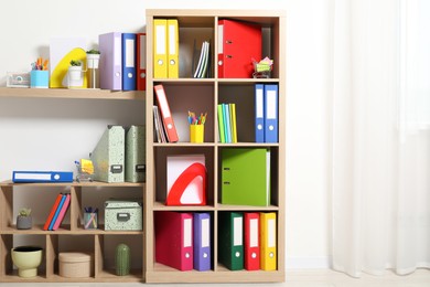 Colorful binder office folders and other stationery on shelving unit indoors