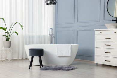 Photo of Stylish bathroom interior with beautiful tub, stool and houseplant