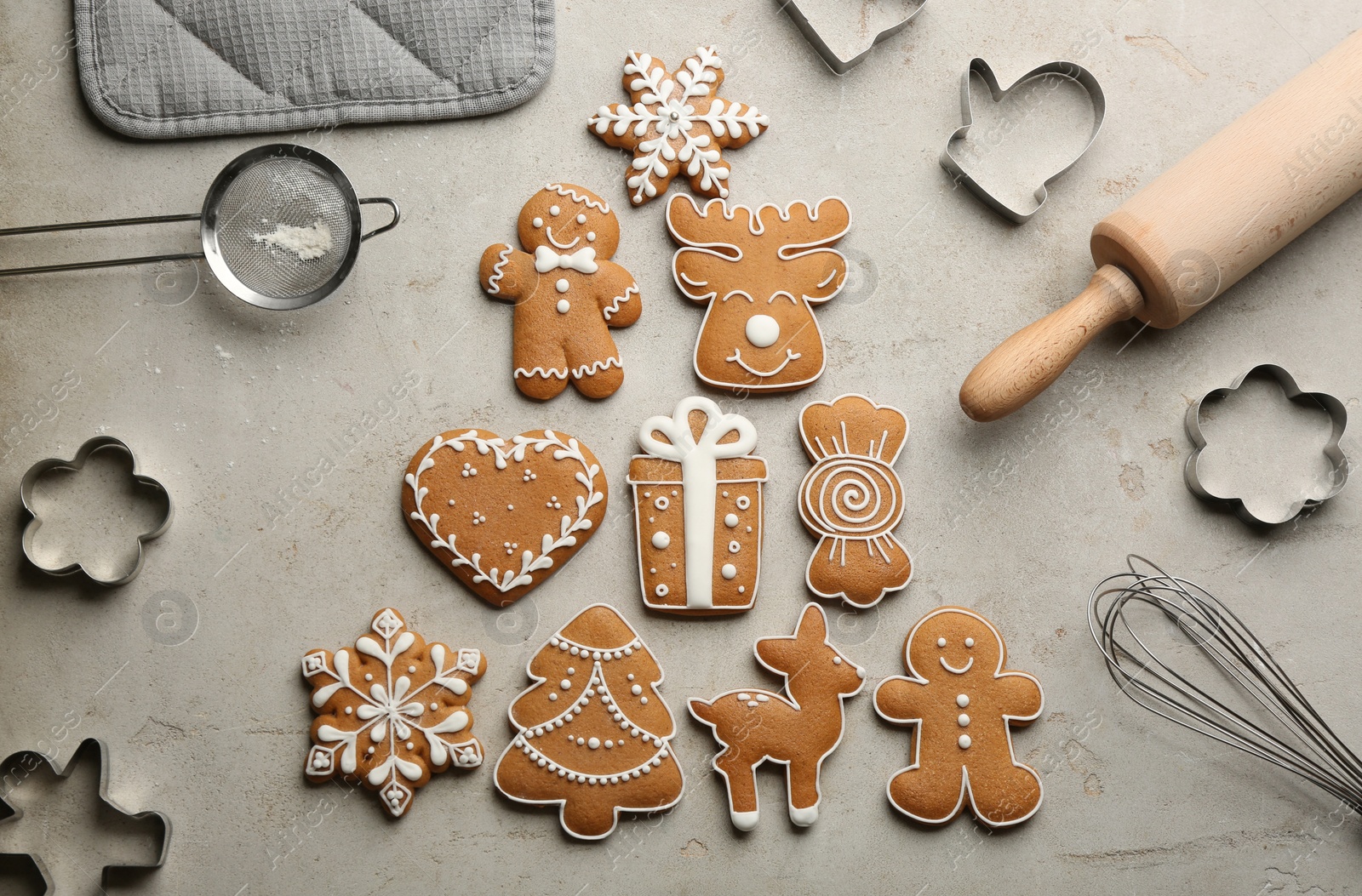 Photo of Christmas tree made of delicious gingerbread cookies surrounded by kitchen utensils on light table, flat lay