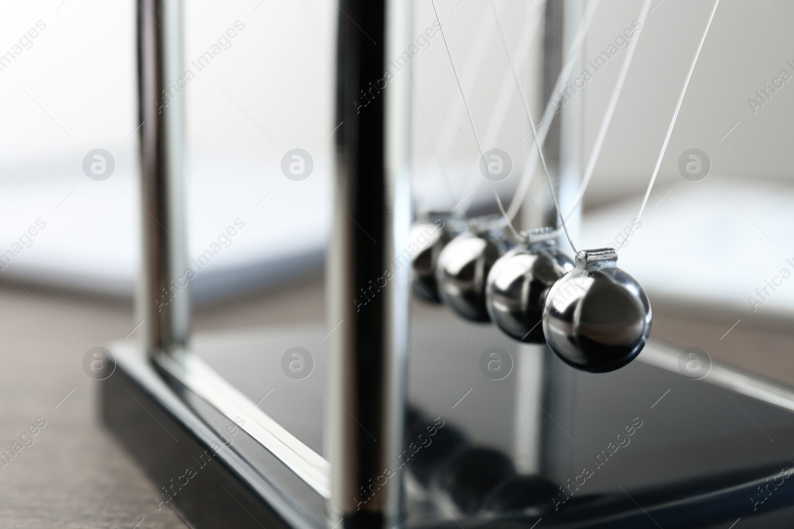 Photo of Newton's cradle on wooden table, closeup. Physics law of energy conservation