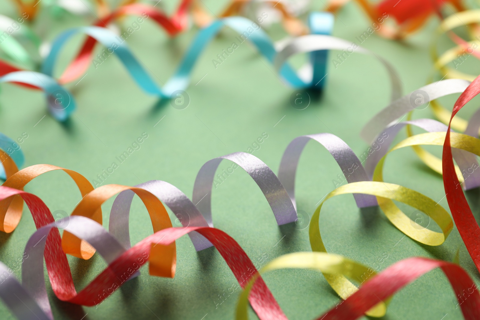 Photo of Colorful serpentine streamers on green background, closeup