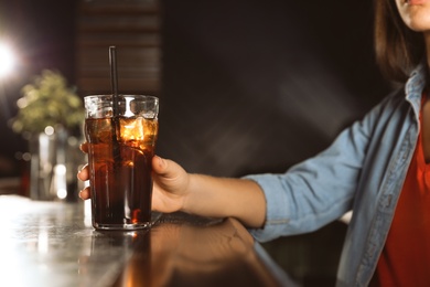 Photo of Woman with glass of refreshing cola at bar counter, closeup