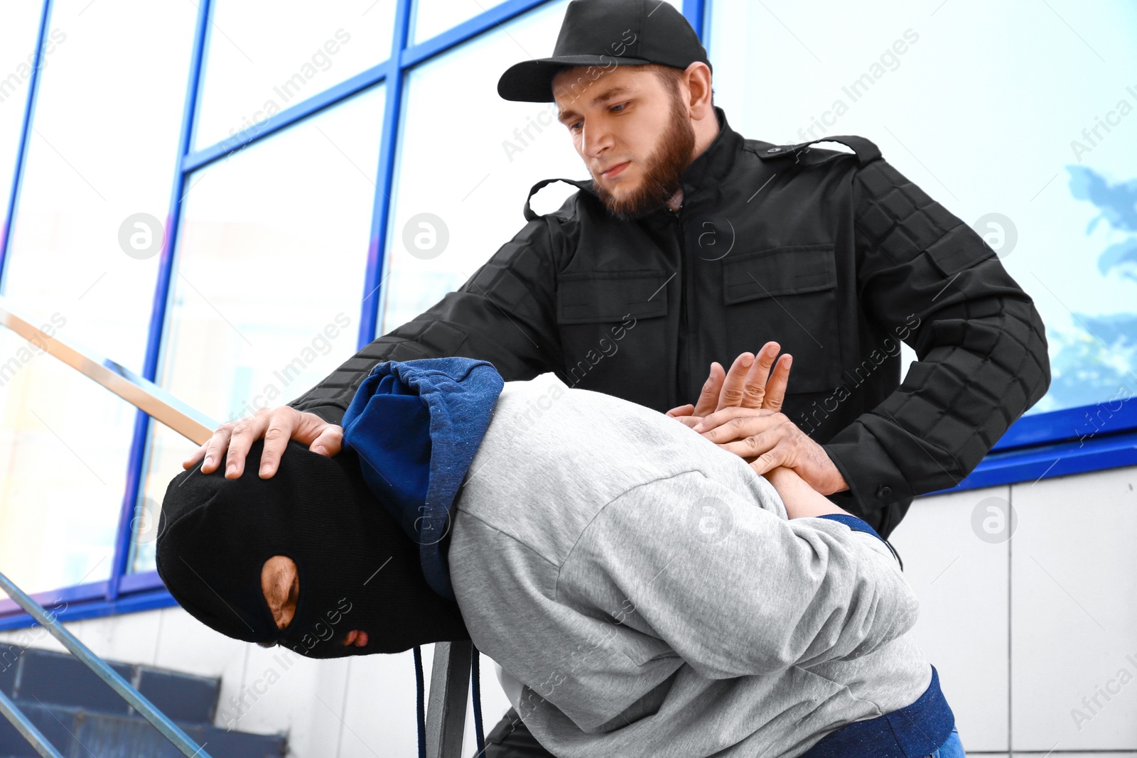 Photo of Police officer arresting masked criminal outdoors