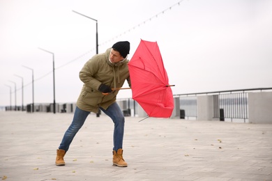 Man with red umbrella caught in gust of wind outdoors