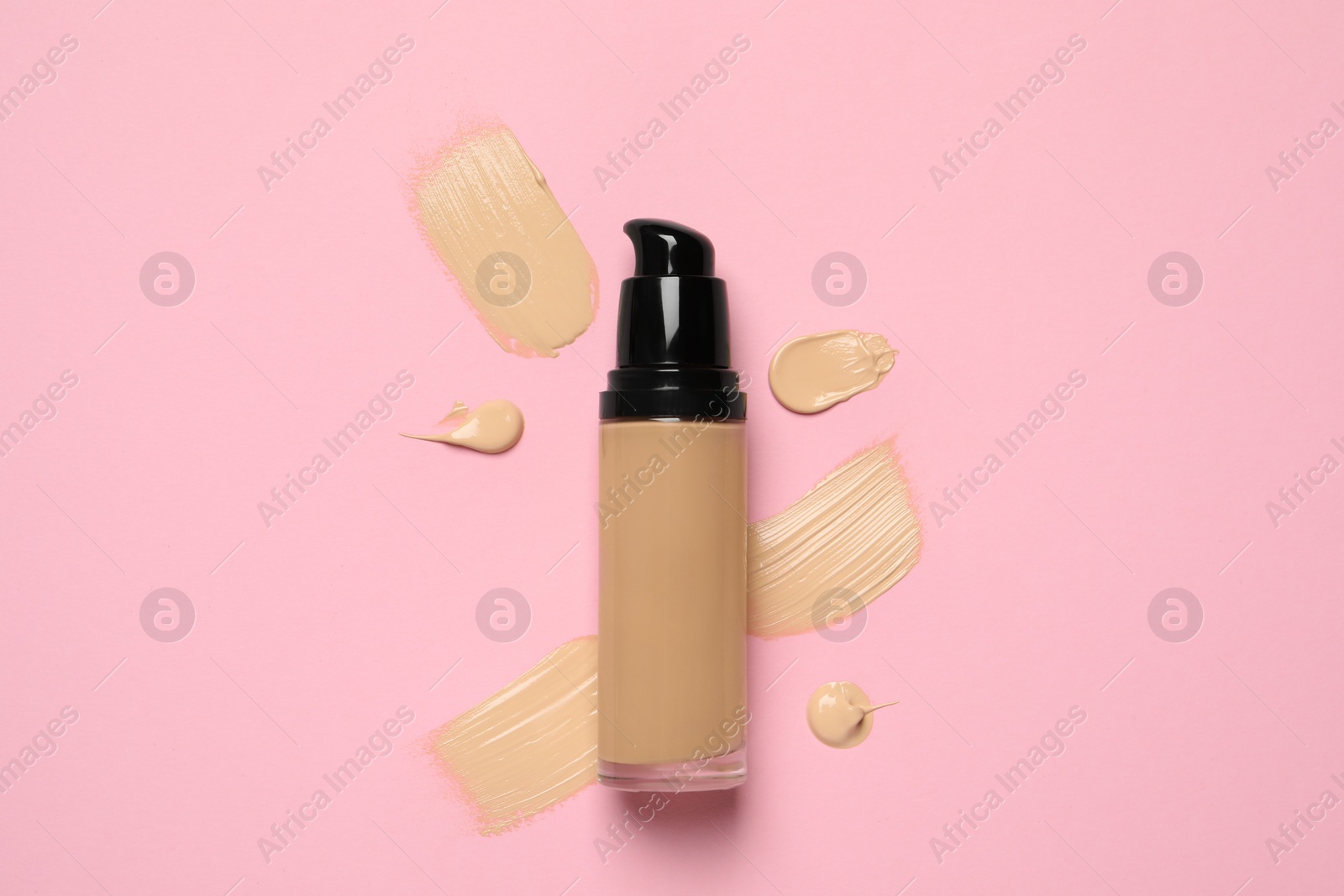 Photo of Liquid foundation and swatches on pink background, top view