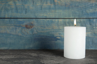 Alight wax candle on table. Space for text