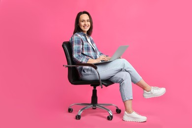 Photo of Mature woman with laptop sitting in comfortable office chair on pink background