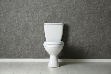 New toilet bowl near grey wall indoors