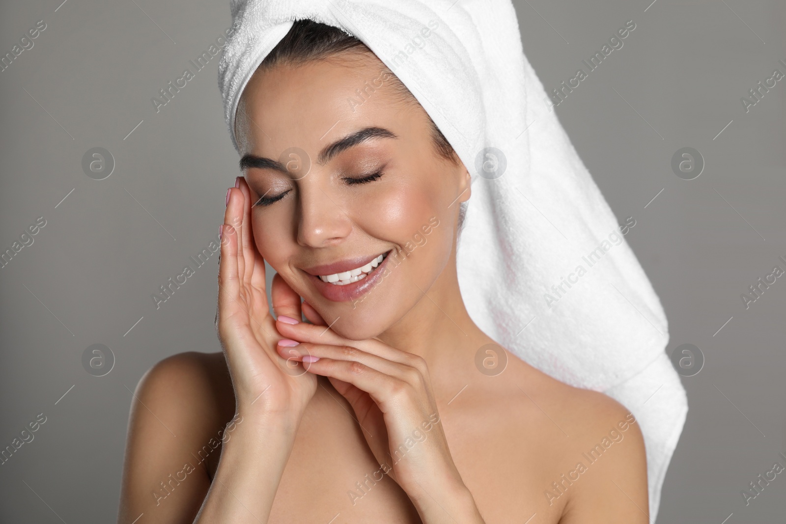 Photo of Beautiful young woman with towel on head against grey background