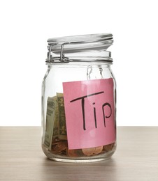 Photo of Tip jar with money on wooden table against white background