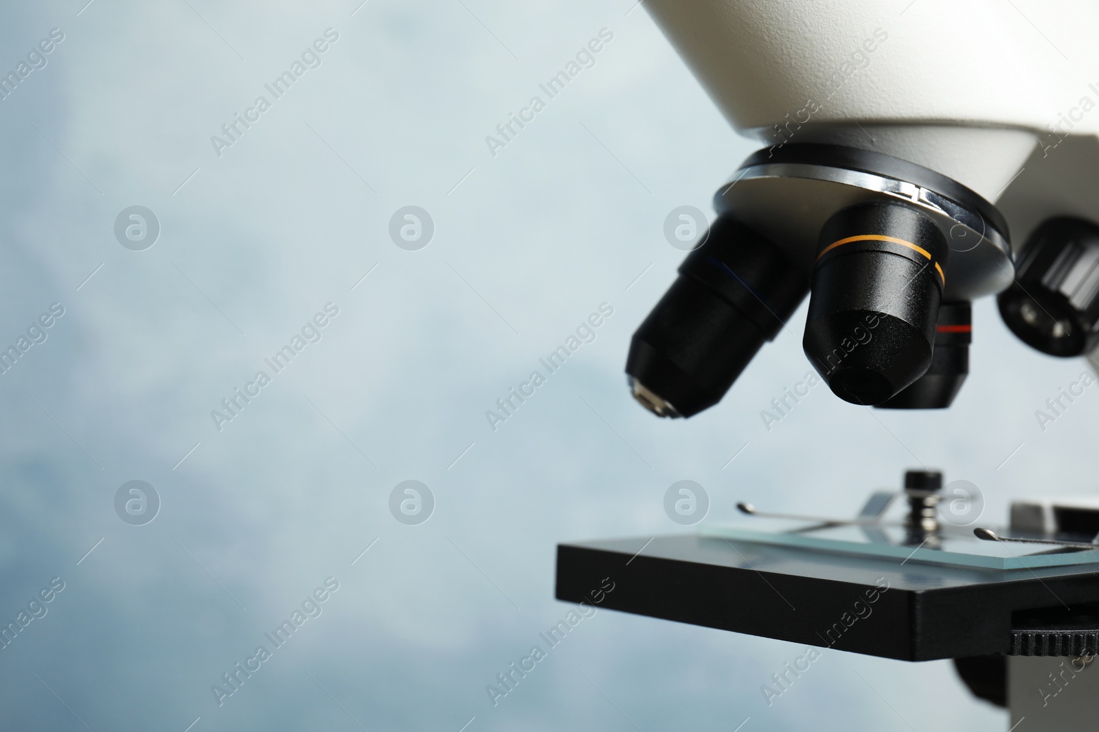 Photo of Closeup view of modern microscope on blue background, space for text. Medical equipment