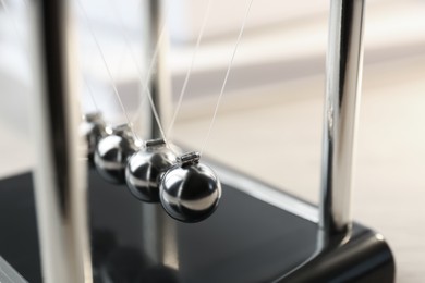 Photo of Newton's cradle on table, closeup. Physics law of energy conservation