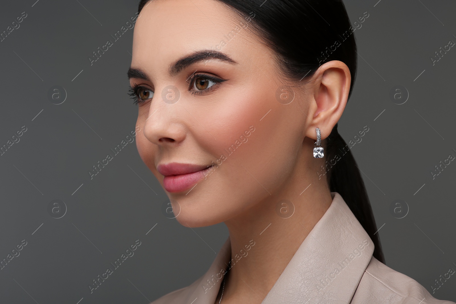 Photo of Beautiful young woman with elegant earrings on dark grey background, closeup
