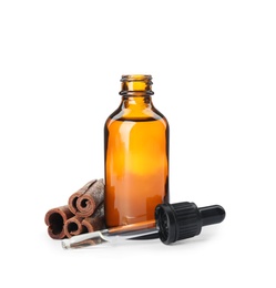 Photo of Bottle of essential oil and cinnamon sticks on white background