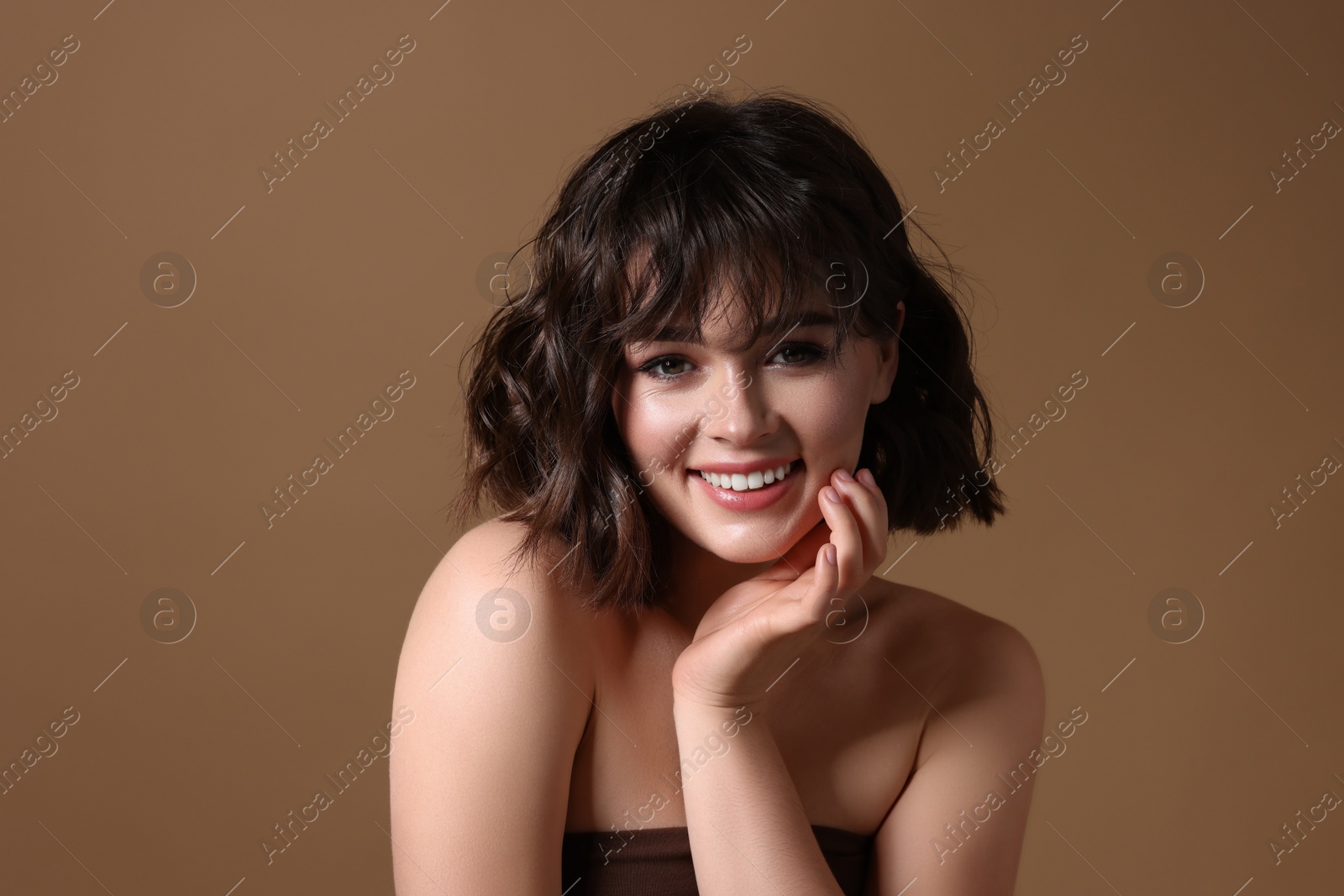 Photo of Portrait of beautiful young woman with wavy hairstyle on brown background