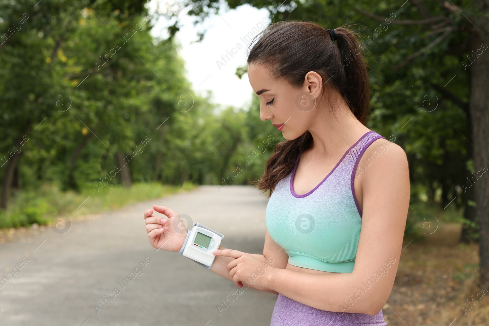 Photo of Young woman checking pulse with medical device after training in park. Space for text