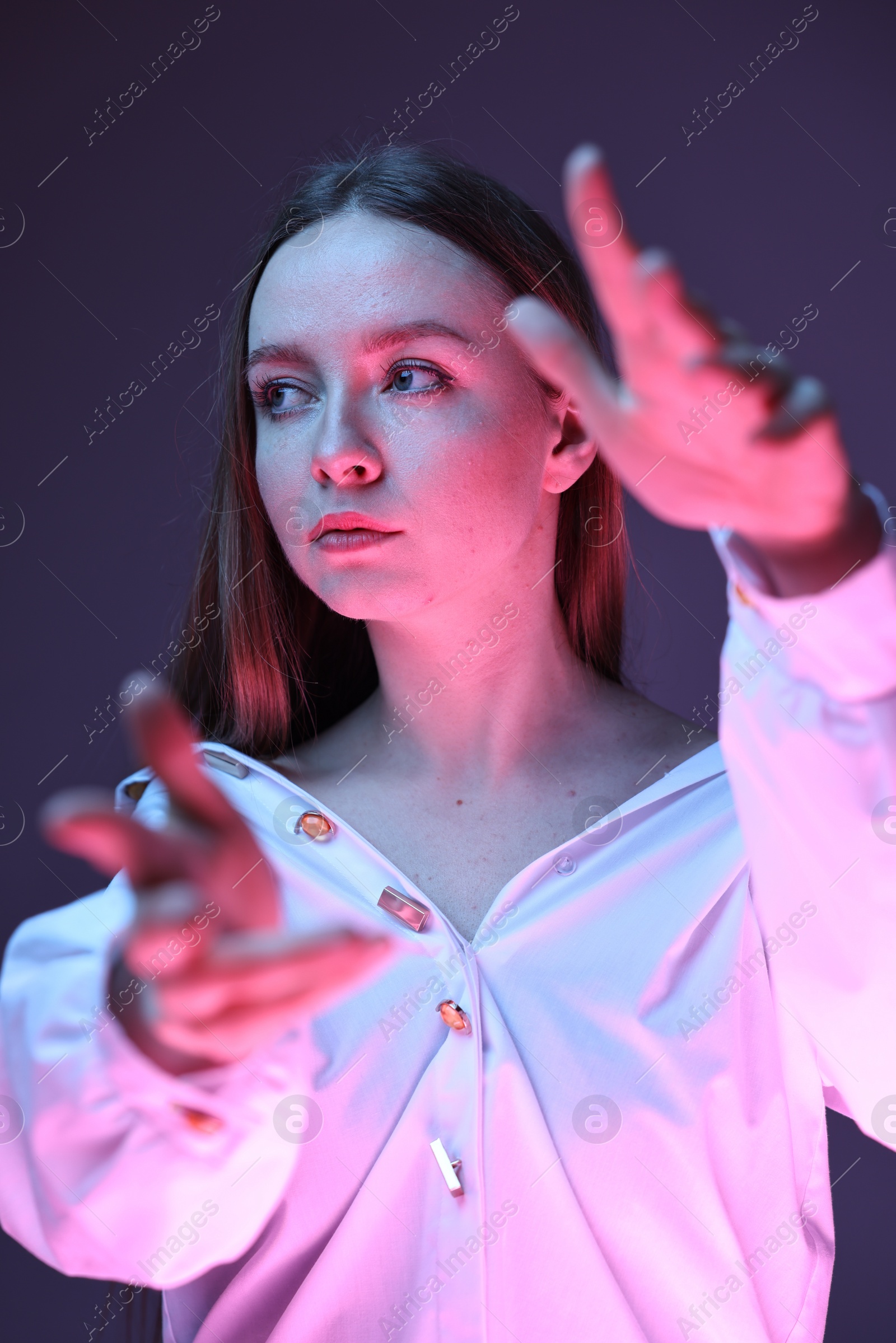 Photo of Fashionable portrait of beautiful young woman on purple background in neon lights