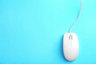 Modern wired mouse on light blue background, top view. Space for text