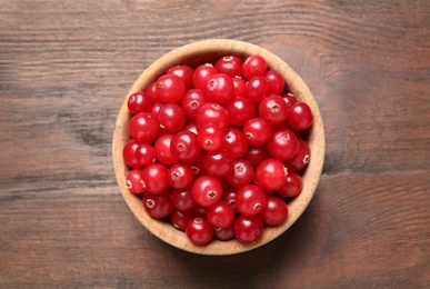 Photo of Tasty ripe cranberries on brown wooden table, top view