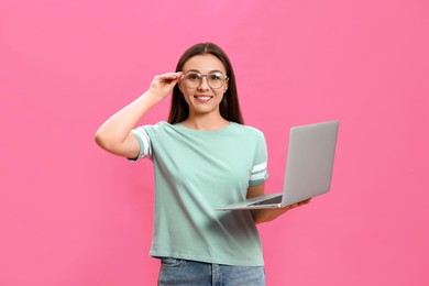 Young woman with modern laptop on pink background