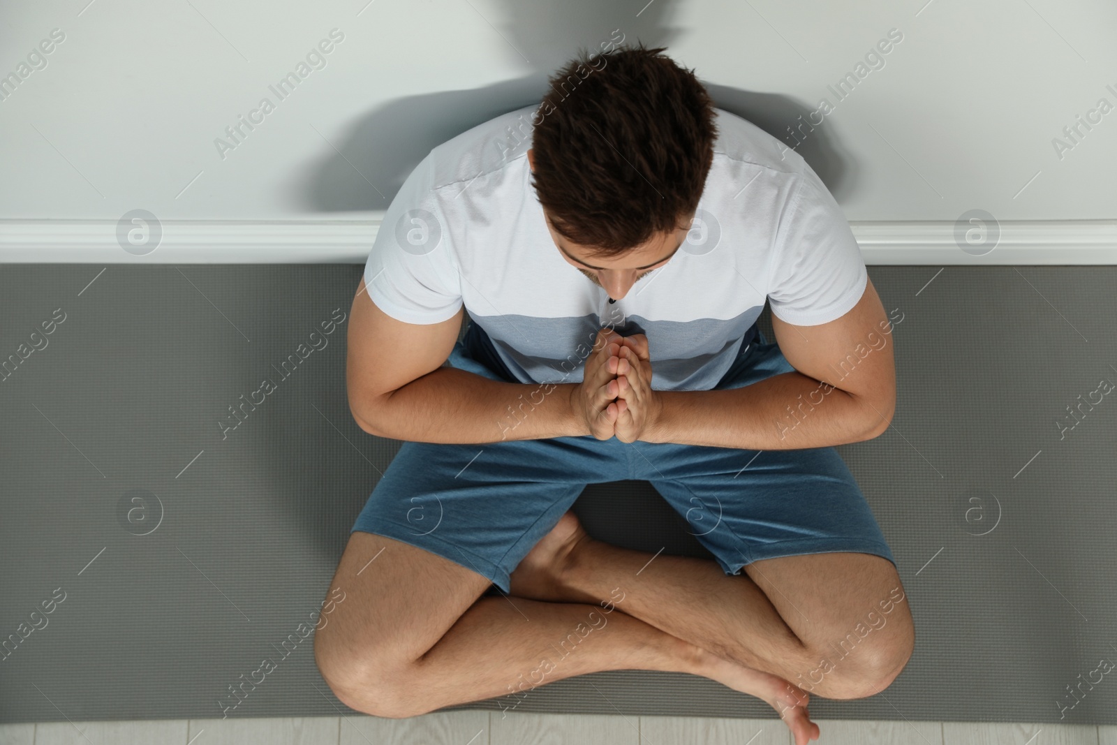 Photo of Young man practicing zen yoga near wall indoors, above view