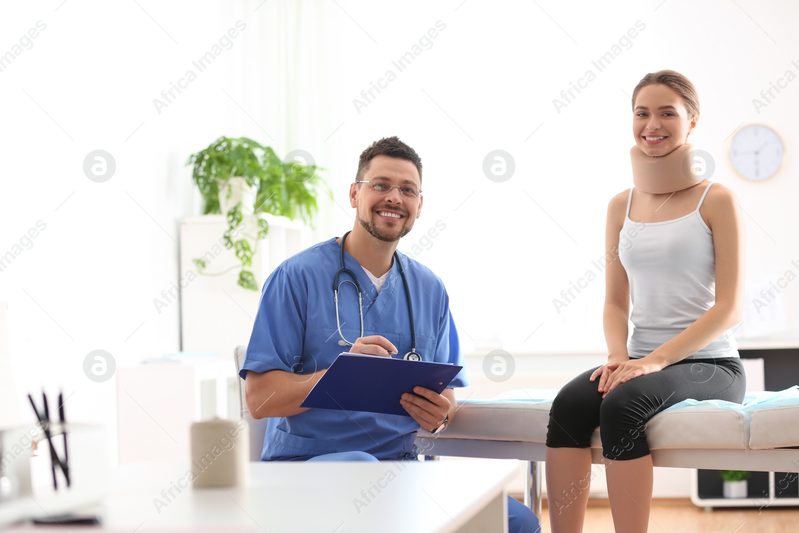 Photo of Male orthopedist examining patient with injured neck in clinic