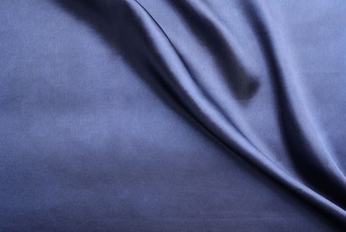 Photo of Crumpled dark blue silk fabric as background, top view. Space for text