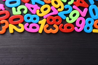 Colorful numbers on dark wooden school desk, flat lay. Space for text