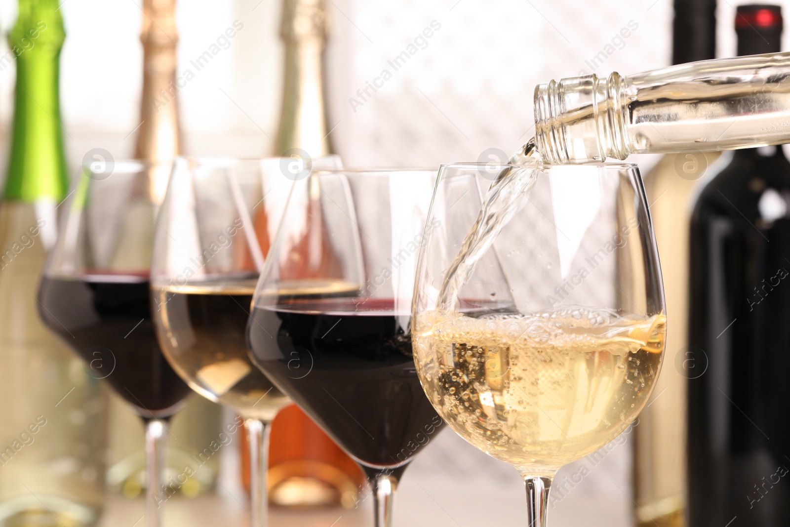 Photo of Pouring white wine from bottle into glass, closeup