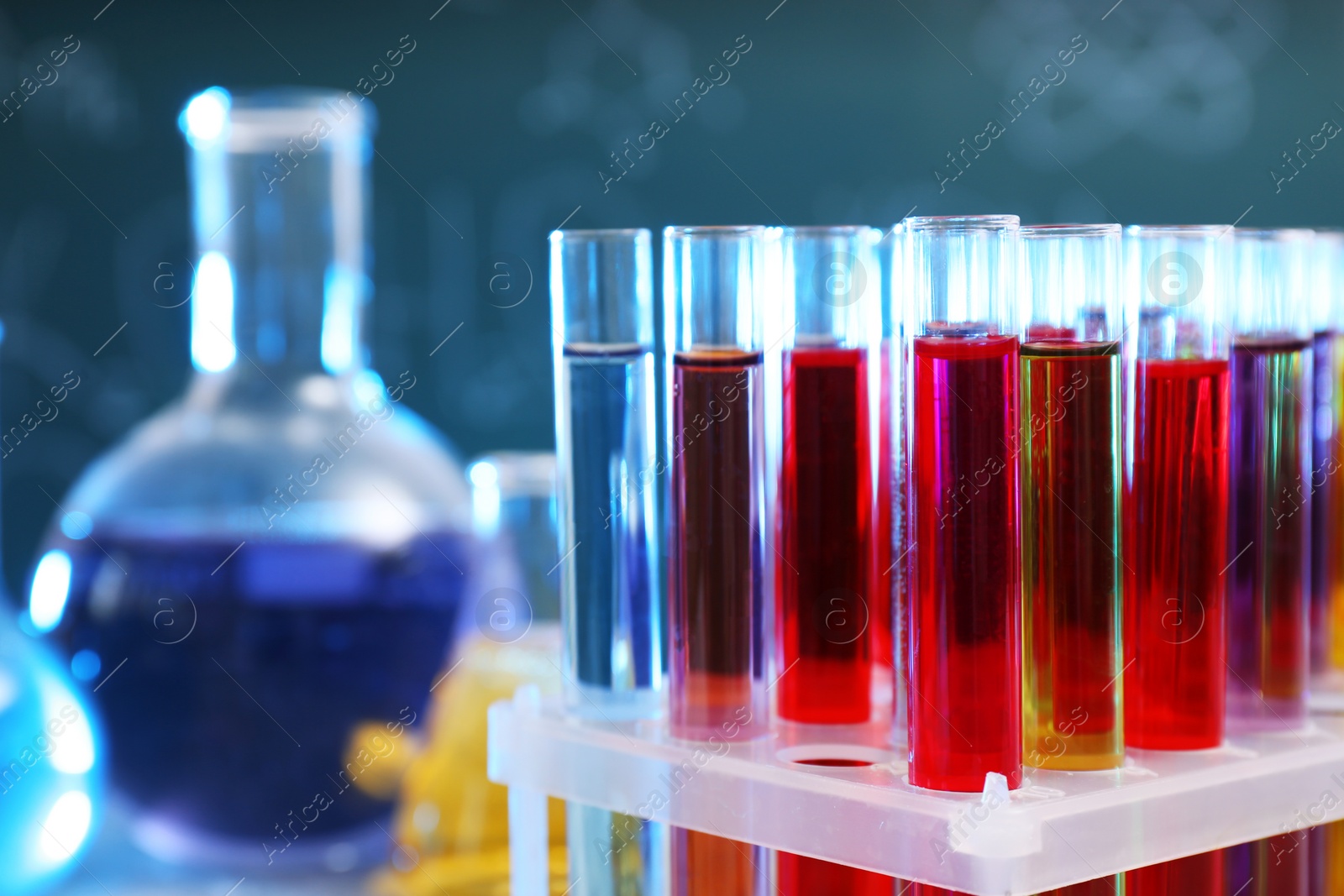 Photo of Closeup of test tubes in rack against blurred background, space for text. Chemistry glassware