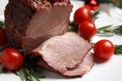 Photo of Cut delicious ham with rosemary and tomatoes on white plate, closeup